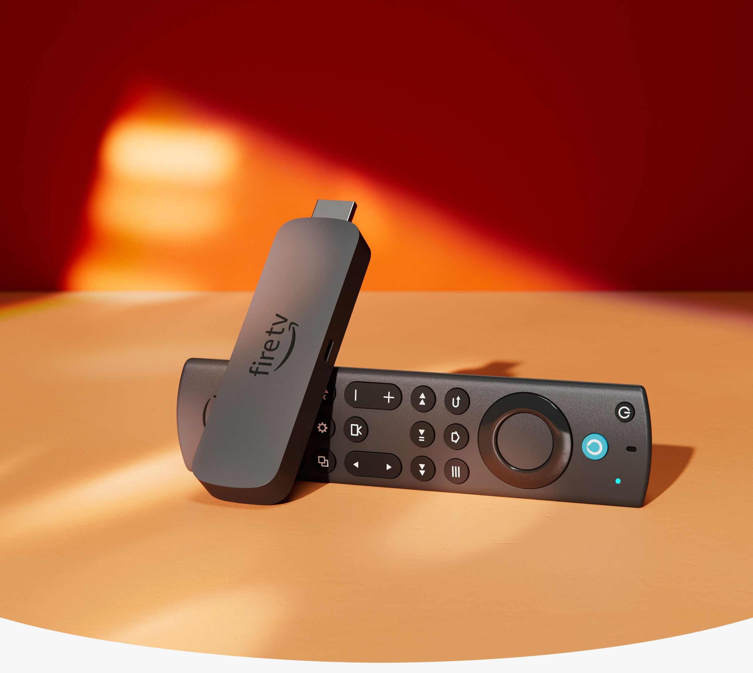 Fire TV Stick (4k Max): Candy bar-shaped device with an HDMI connector on one end and a USB-C socket on the side, with Fire TV Alexa Voice Remote Enhanced: with a navigation ring and buttons on the front and a rounded back.
